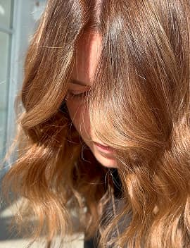 Warm caramel-brown tint colour with soft waves on mid-length hair at Jura Draco Gold Coast