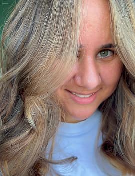 Smiling woman with dimensional blonde highlights and soft waves at Jura Draco Gold Coast