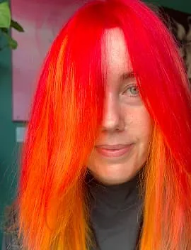 Bright red and orange creative colour on long straight hair by Jura Draco Gold Coast