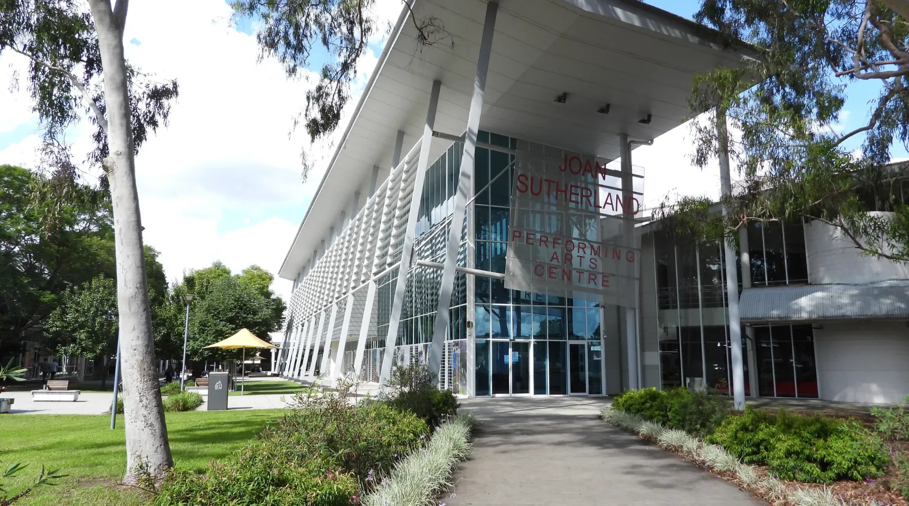 Modern car dealership building with large glass windows and signs for Mercedes-Benz and Marshalls.