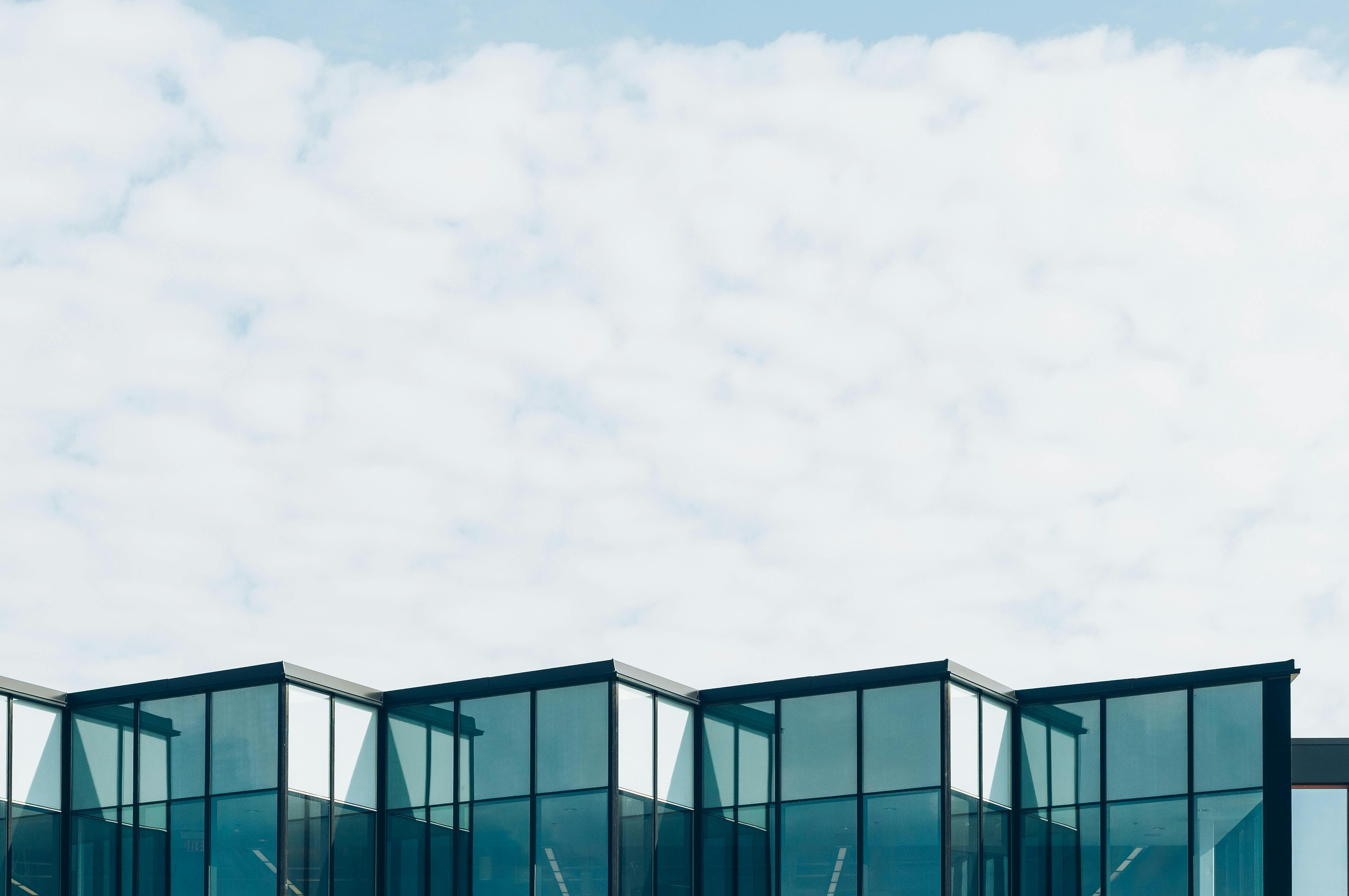 Modern building facade with angular glass windows under a partly cloudy sky.