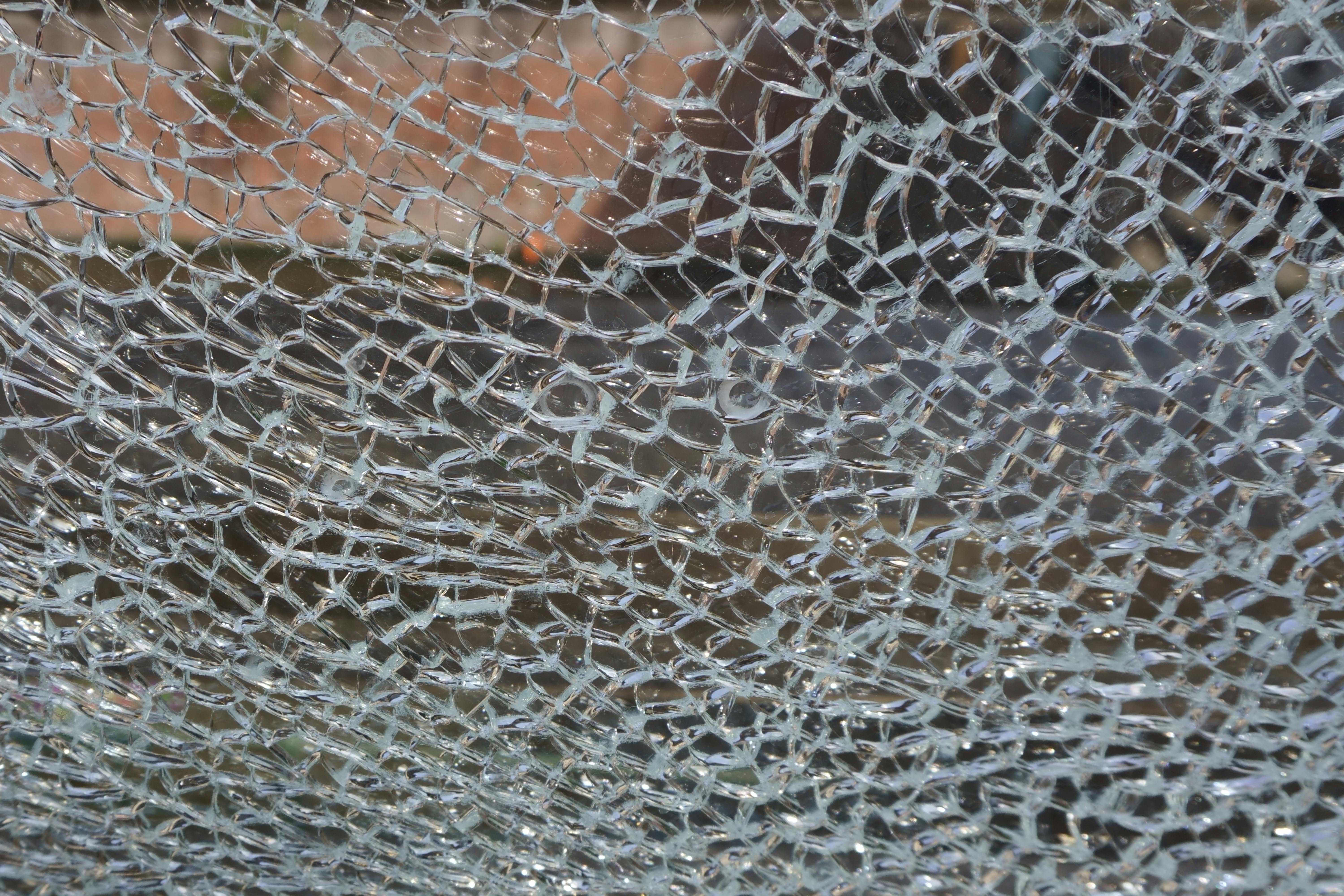 Close-up of shattered glass with intricate cracks radiating from an impact point.