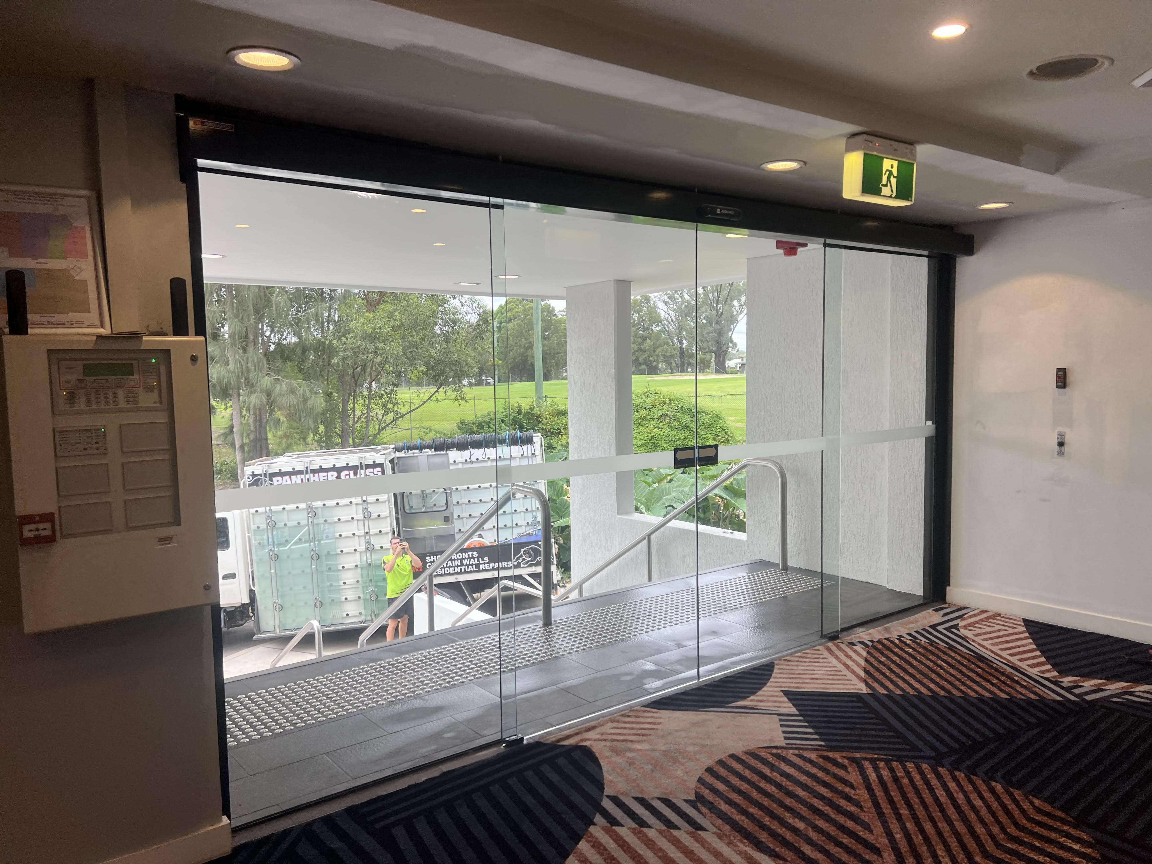 Facade of a modern building with large reflective glass windows and an upper pentagon-shaped window.
