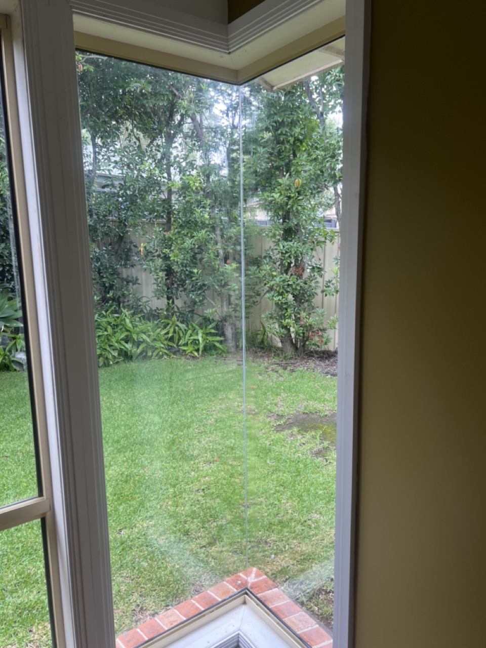 Three workers on an orange scissor lift installing glass panels on a building facade with a Panther Glass sign.