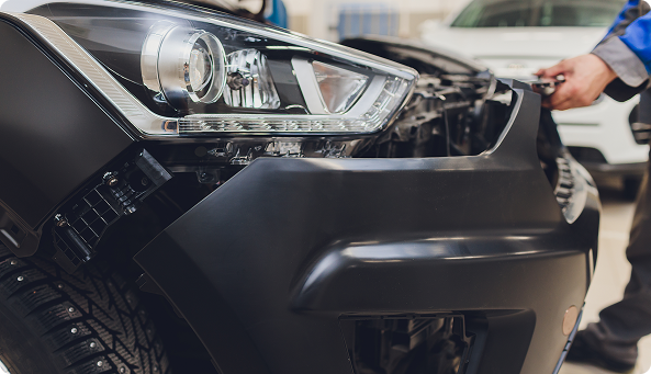 Picture of a worker taking off a bumper from a car.