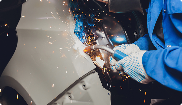 Worker welding the side of a car.