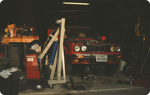A picture of an old, red BMW M3 in the garage of Ray's old home.