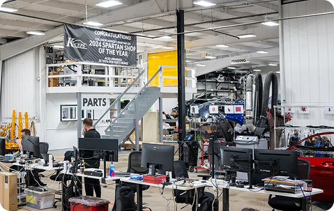 Inside the K-ceps Granville Auto Body shop, with the Spartan Award banner in view, hanging from the rafters of the large open area.