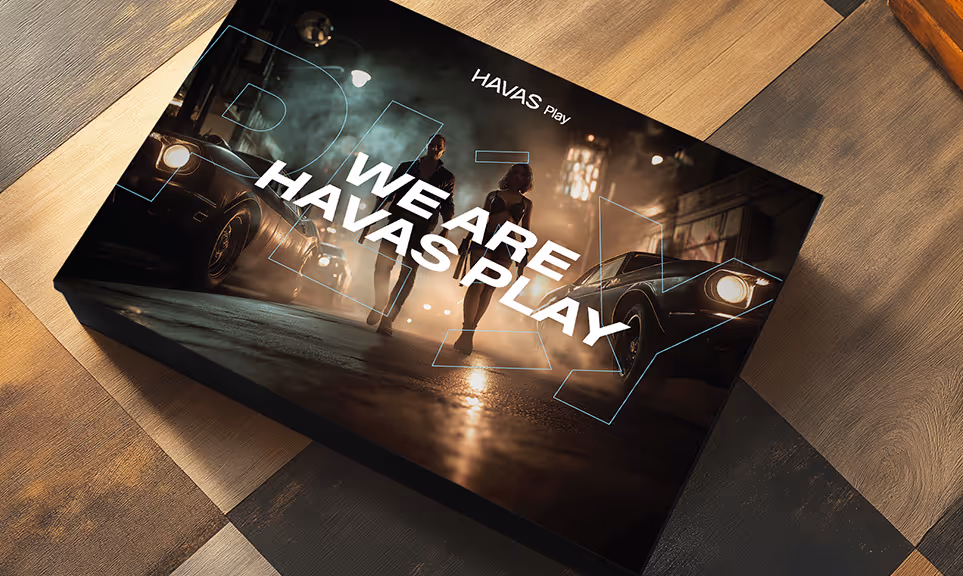 Box with a night street scene showing two people walking between vintage cars, text on box reads 'We are Havas Play'.