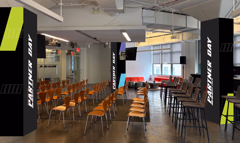 Modern event space with rows of wooden chairs and tall stools, pillars displaying 'Partner Day' signage.