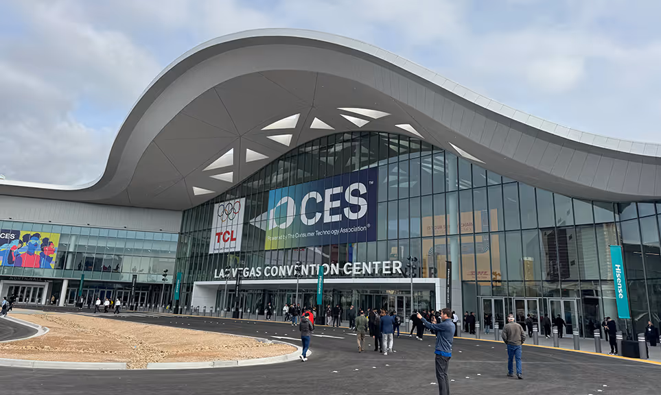 Entrance of Las Vegas Convention Center with CES and TCL banners, people walking outside under a large modern curved roof.