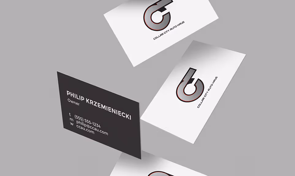 Three floating business cards for Collar City Auto Haus; one black card with contact details of Philip Krzemieniecki, Owner, and two white cards showing the company logo.