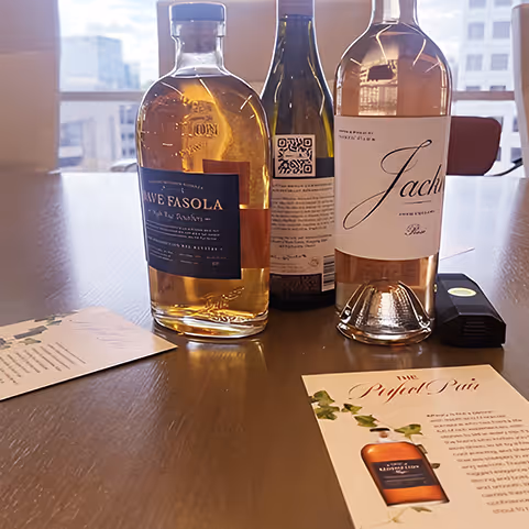Three bottles of liquor, including a bottle labeled 'Jach,' displayed on a wooden table with pamphlets and a remote control.