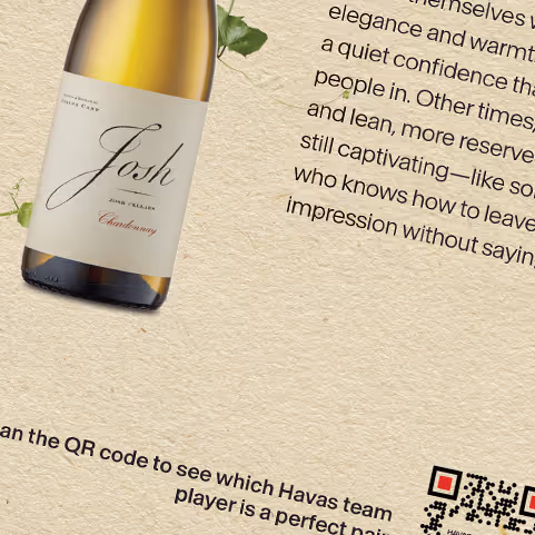 Bottle of Josh Chardonnay wine tilted on a textured beige background with partially visible text and a QR code.