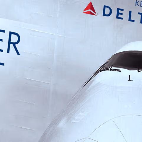 Close-up view of the nose and cockpit windows of a white Delta airplane with the Delta logo in the background.