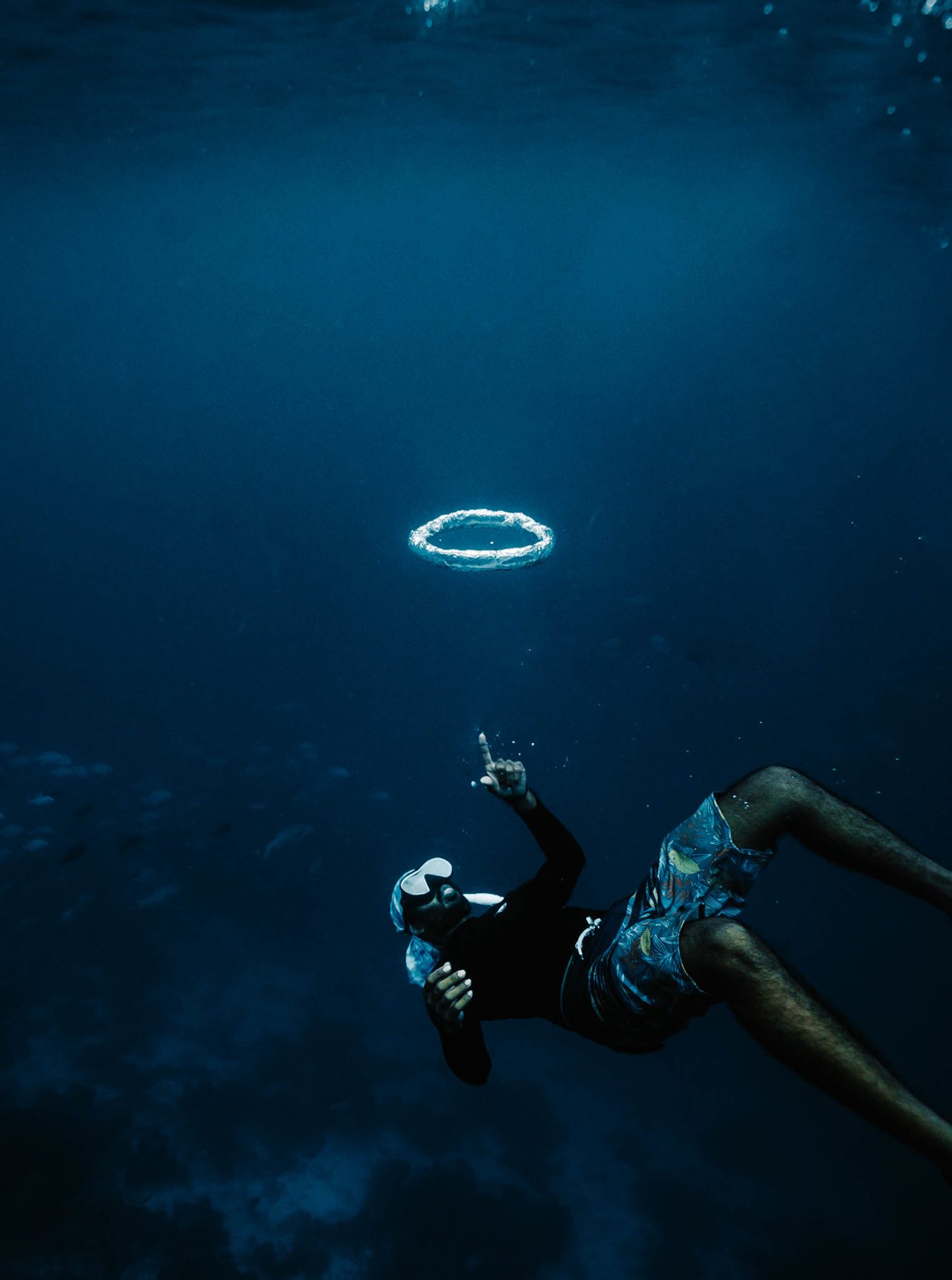 Freediver blowing a bubble ring in clear blue water