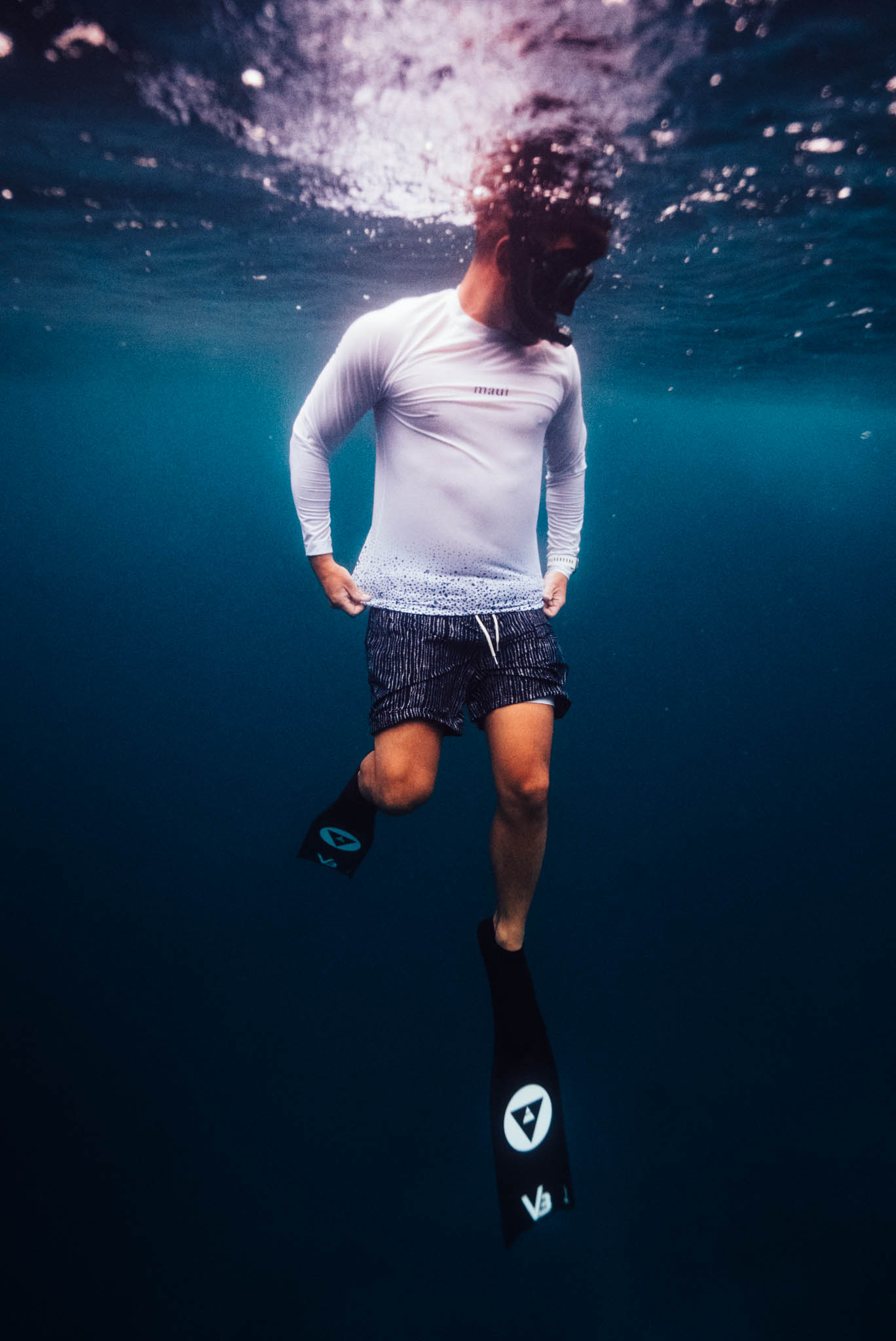 Snorkeler in a white Maui rash guard hanging below the surface
