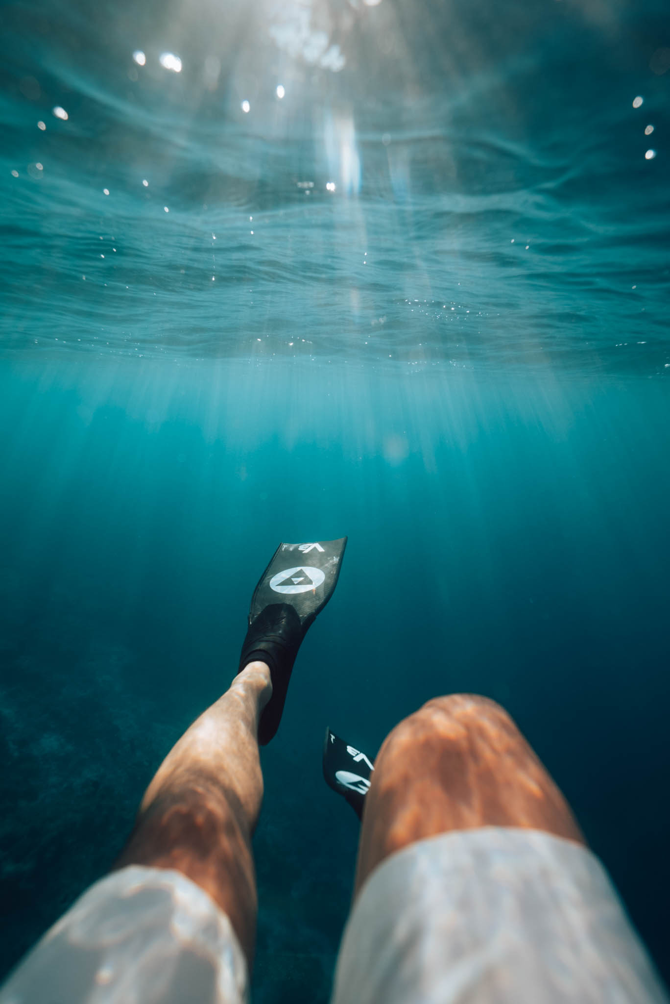 First-person view of one fin kicking in clear blue water