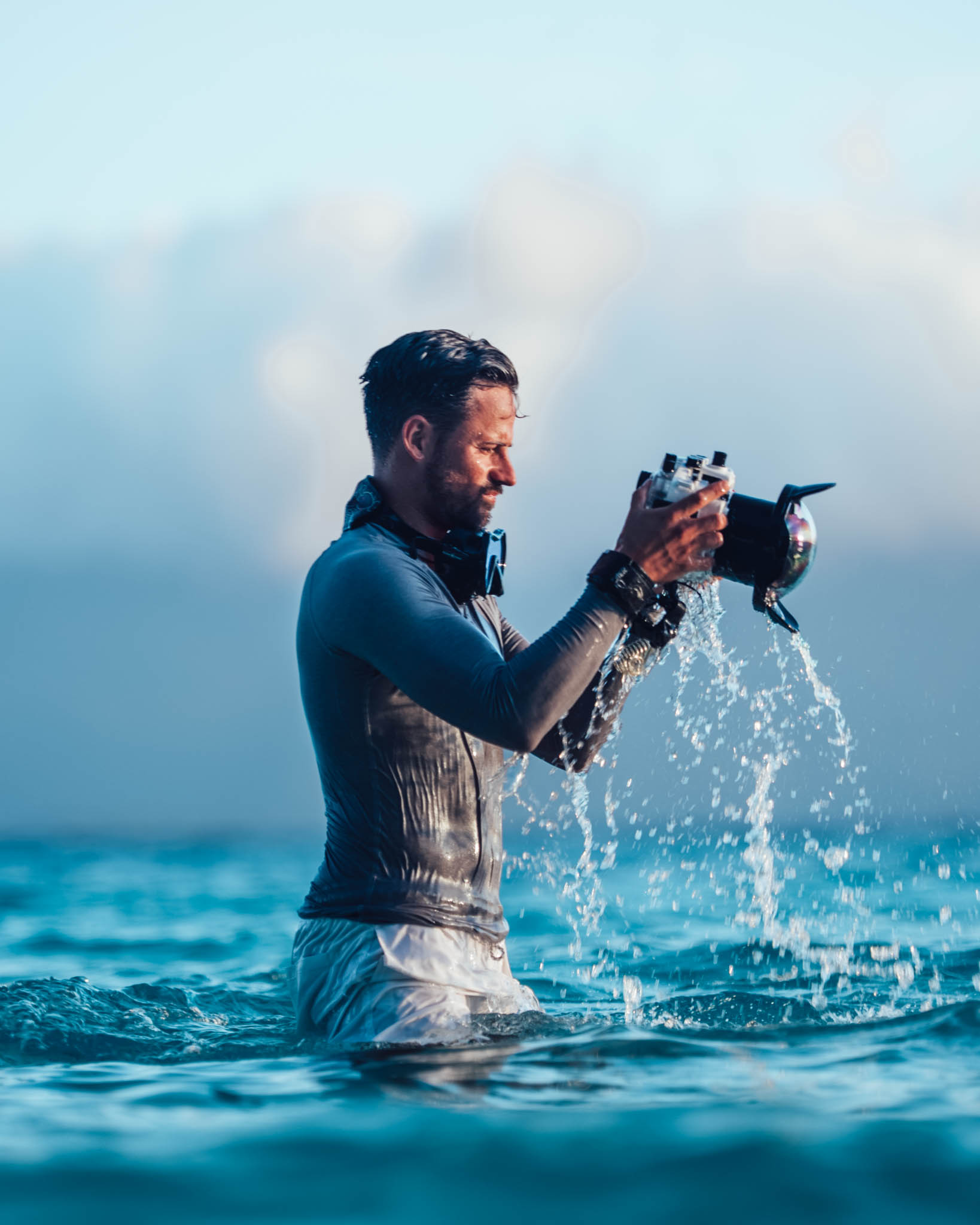 Water pouring off a SeaFrogs housing with a dome port as a snorkeler lifts it out of the sea