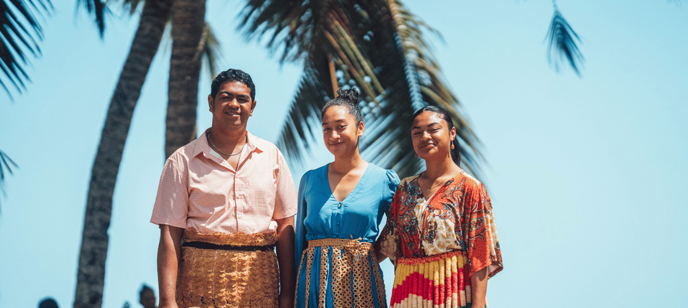 Tongan family in traditional dress under palm trees