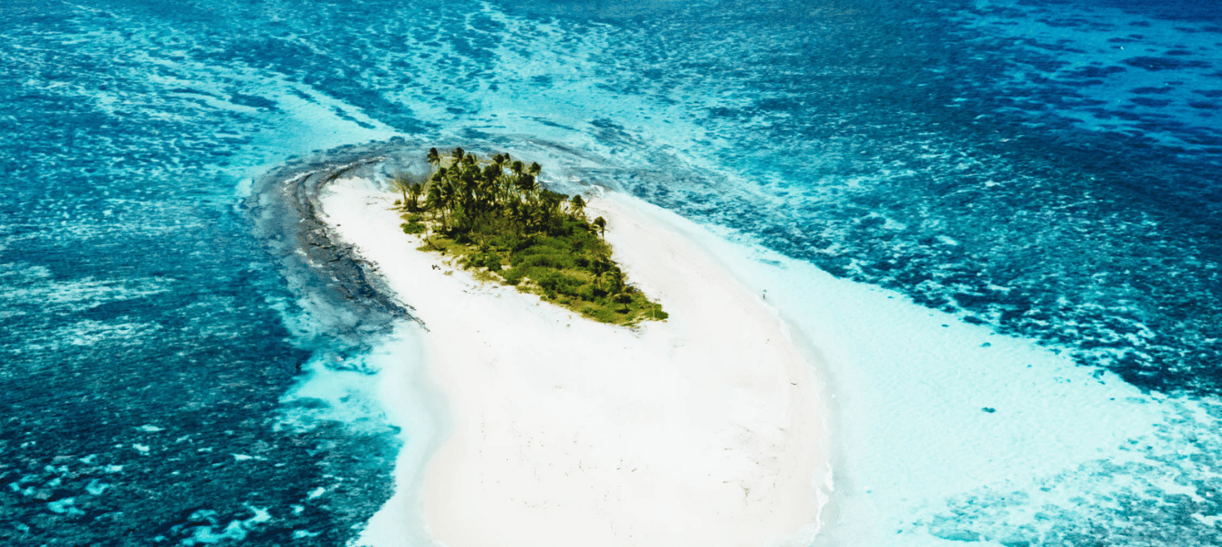 Aerial view of a small sandy island surrounded by reef in Tonga