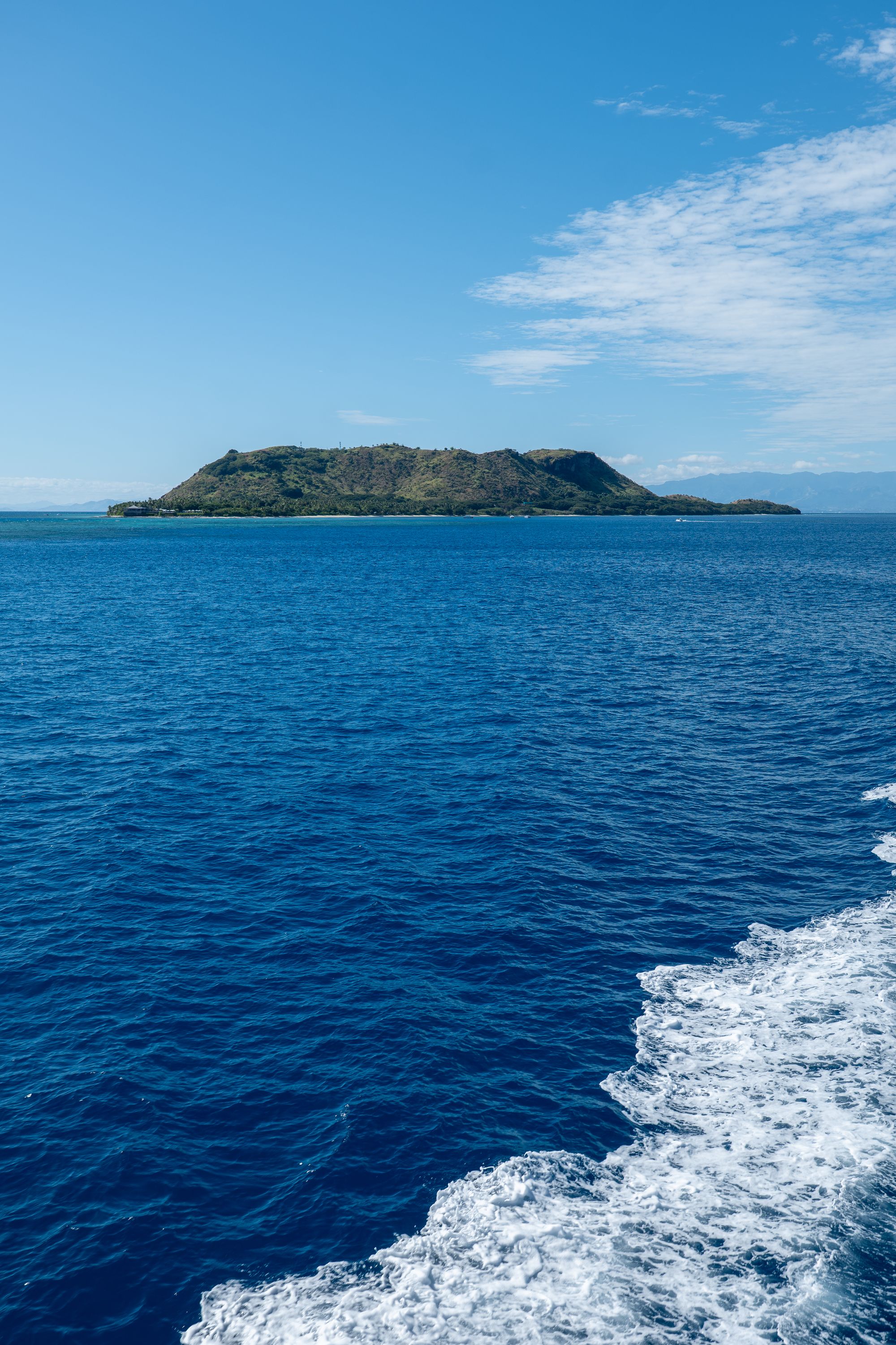Aerial view of a green island surrounded by blue water in Fiji