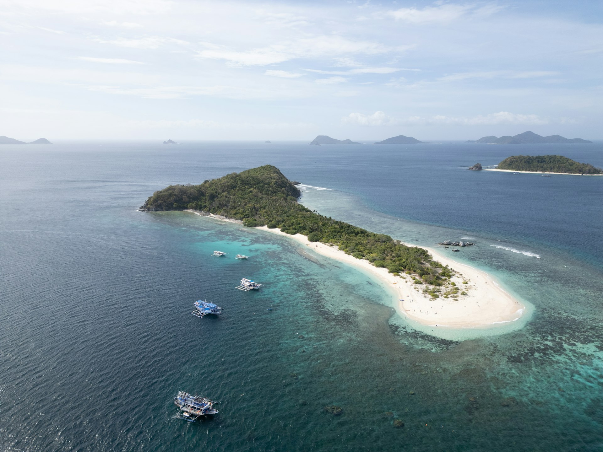 Small island surrounded by turquoise water and boats in Fiji