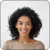 Smiling woman with curly black hair wearing a beige top against a light background.