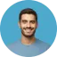Smiling man with short dark hair and beard on a blue circular background.