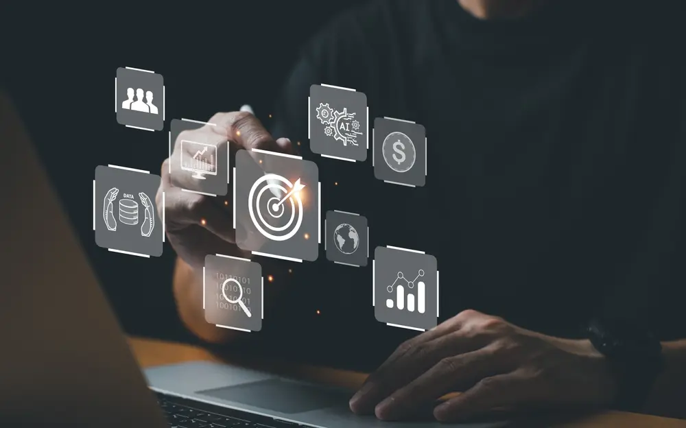 Hands typing on a laptop with glowing holographic AI and data analytics icons floating above the keyboard.