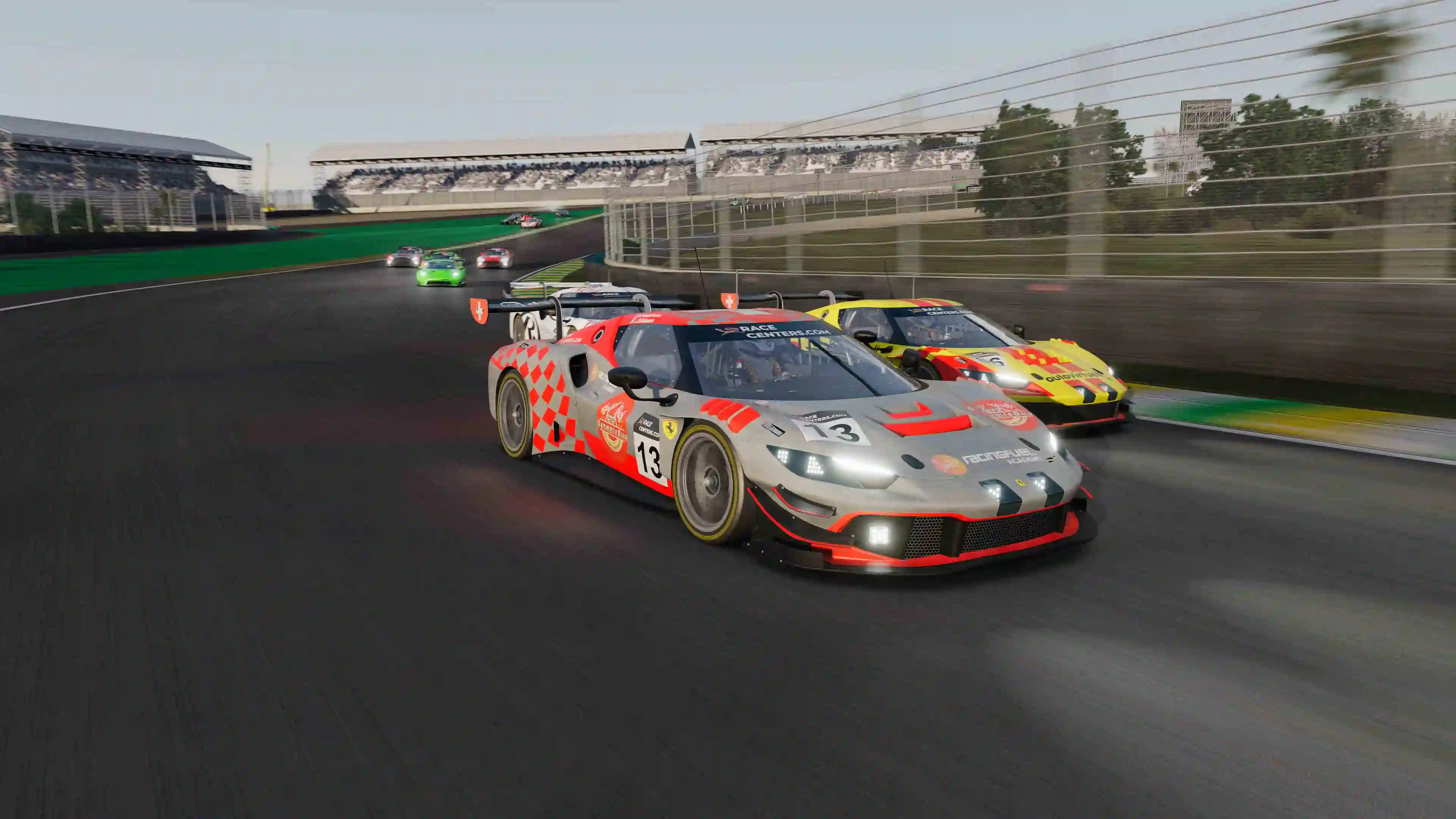 Two Ferrari race cars, one grey with red accents number 13 and one yellow with red accents number 6, race closely on a racetrack with stands and trees in the background.