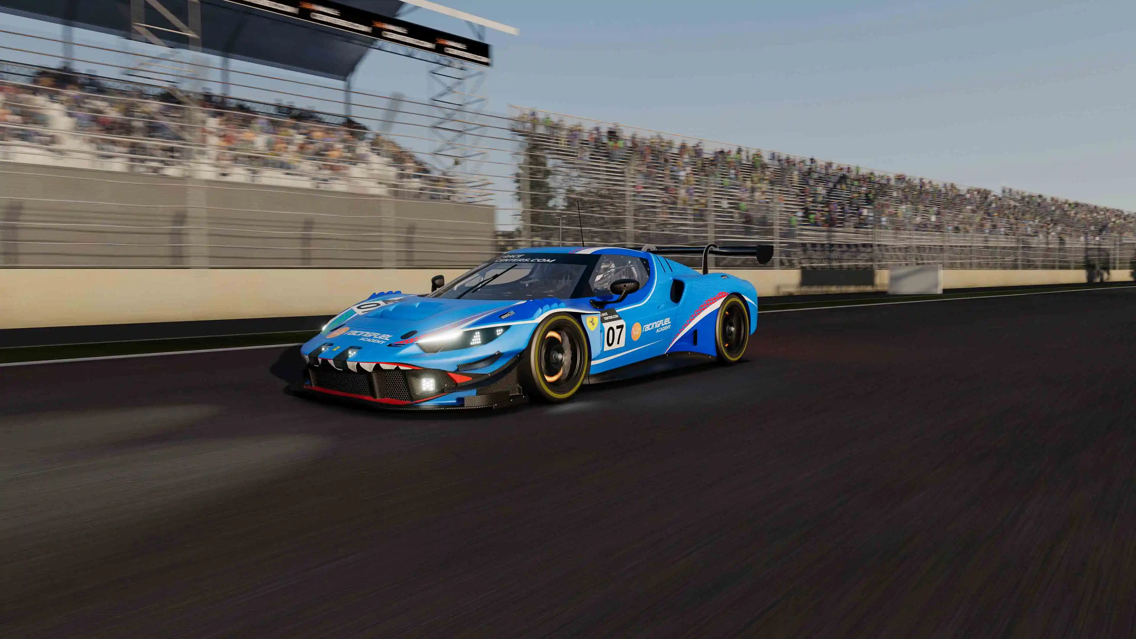 Blue and black race car number 07 speeding on a racetrack with blurred stands in the background.