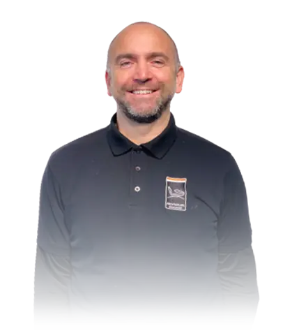 Smiling man with short beard wearing a black collared shirt with a small logo on the chest.