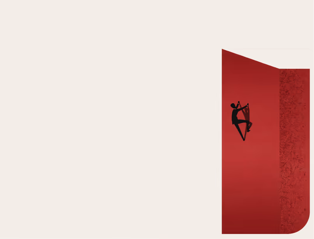 Silhouette of a person rock climbing on a red wall with textured surface.