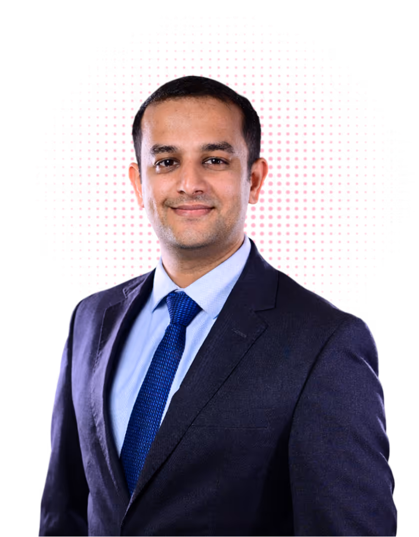 Smiling man in a dark suit, light blue shirt, and blue tie with a digital pink dotted circle behind him.