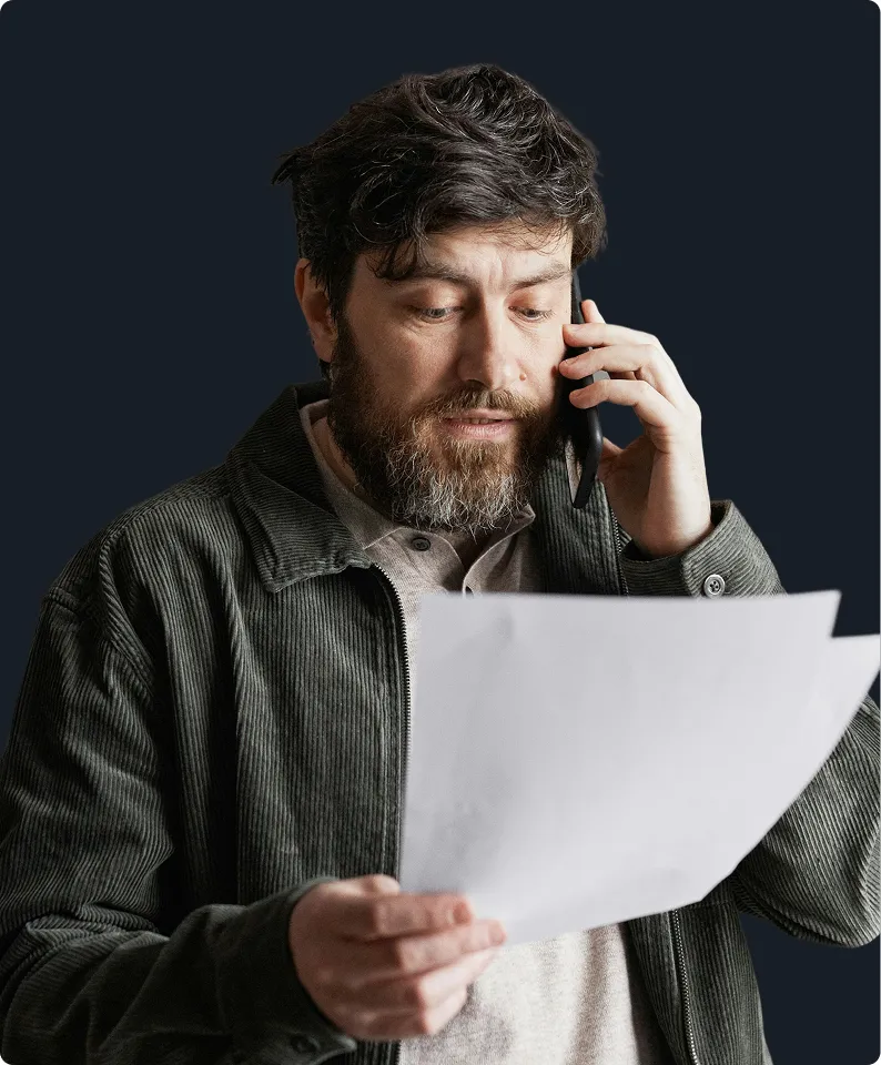 Man reviews documents while on phone, considering custom probiotics for gut health and bloating relief solutions.