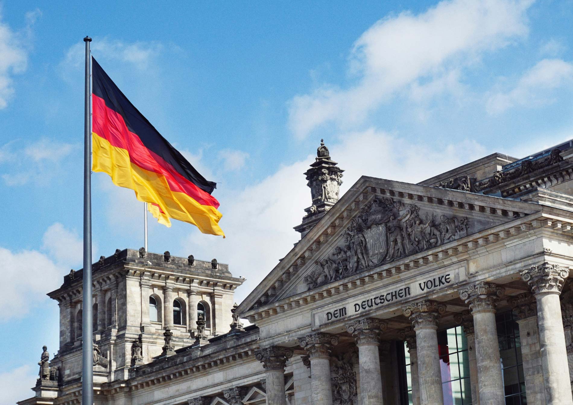 Drapeau allemand devant le Reichstag à Berlin, illustrant une formation d’allemand A1/A2 en ligne.