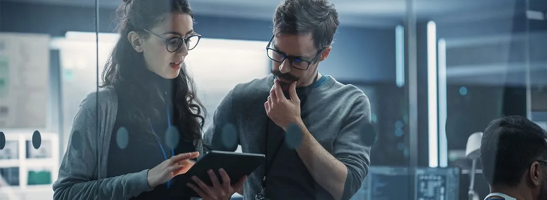 Zwei Menschen, die zusammen auf ein Tablett schauen und sich beraten.