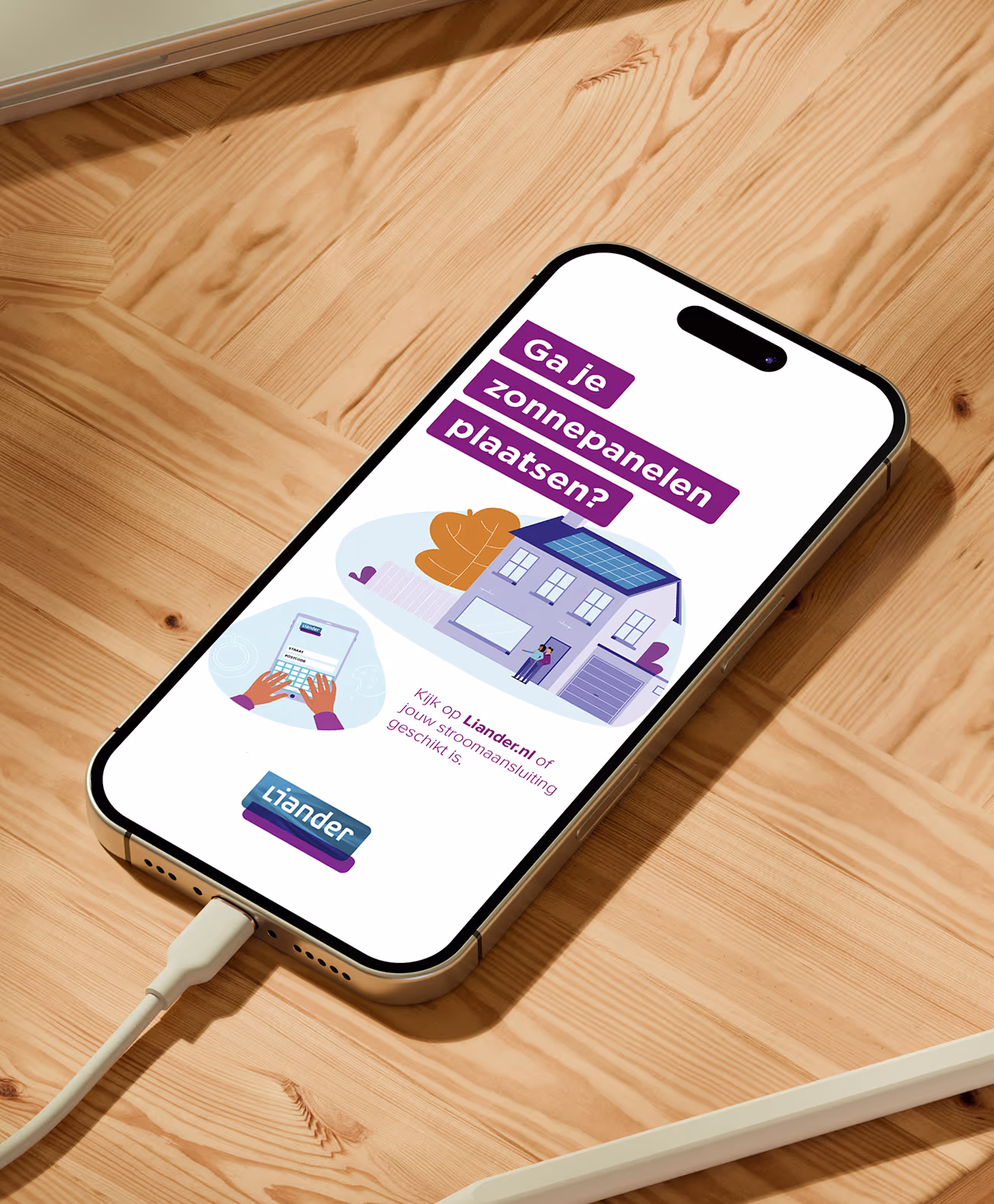 Smartphone on wooden surface displaying an illustration of a house with solar panels and a laptop with text asking if you are going to install solar panels.