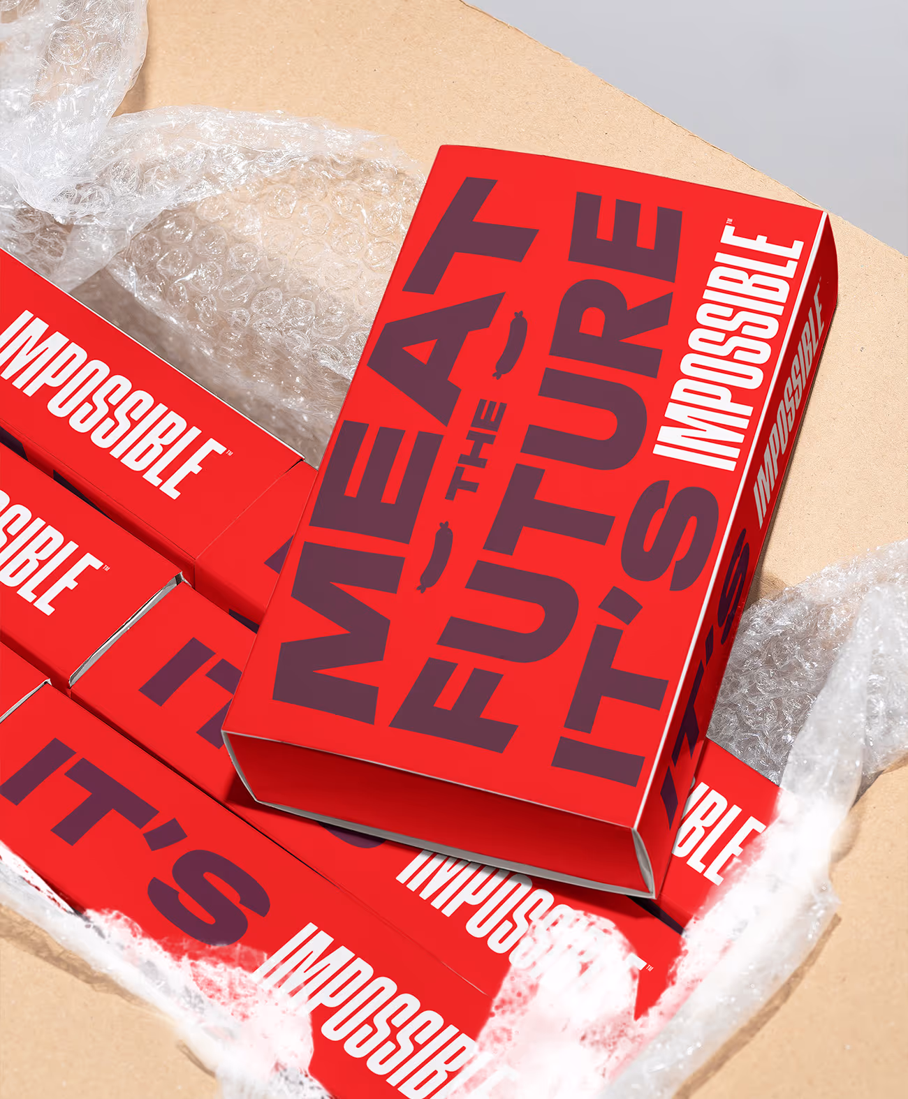 Open cardboard box with red Impossible Foods packaging reading 'MEAT THE FUTURE' in bold letters.