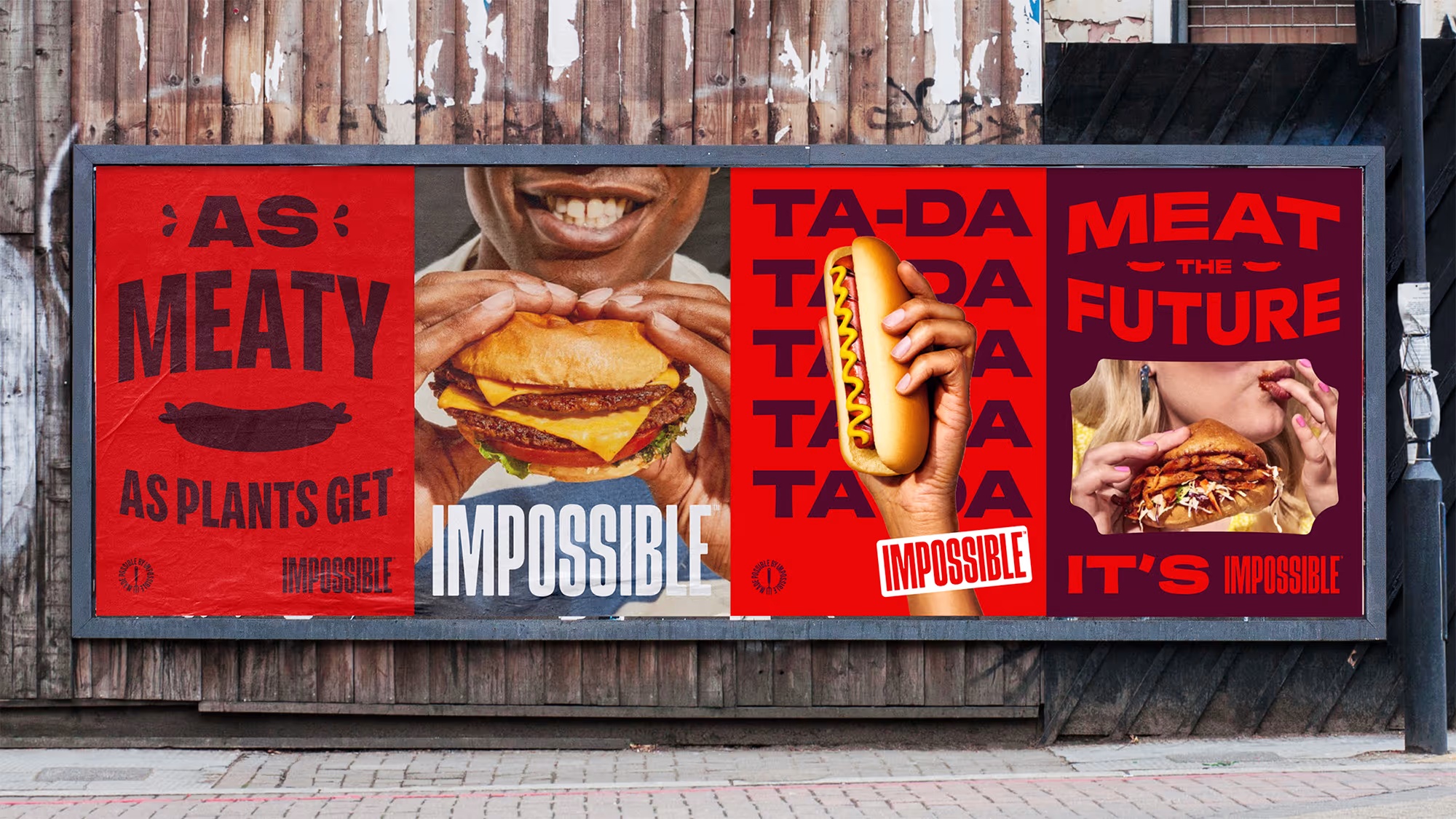 Billboard advertisement for Impossible plant-based meat showing a person holding a cheeseburger, a hand holding a hot dog, and a person eating a sandwich with text promoting meat from plants.