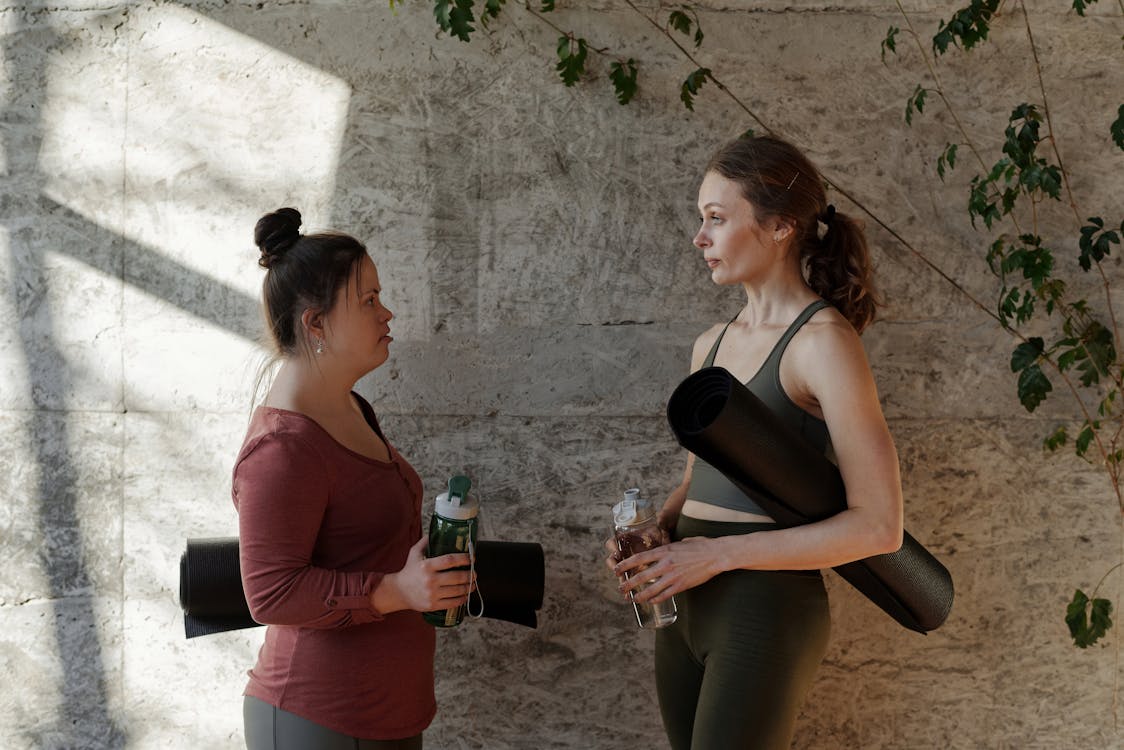 Free Two Women Holding Water Bottle and Yoga Mat Stock Photo
