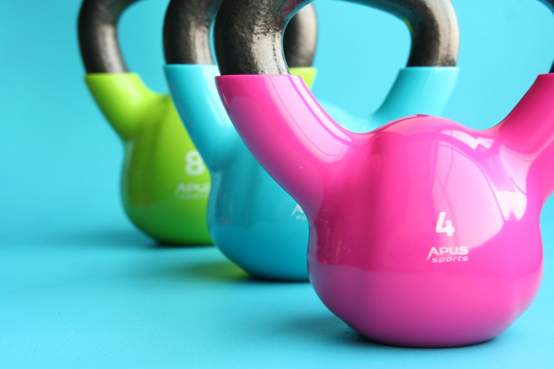 Free Green, Blue, and Pink Kettle Bells on Blue Surface Stock Photo