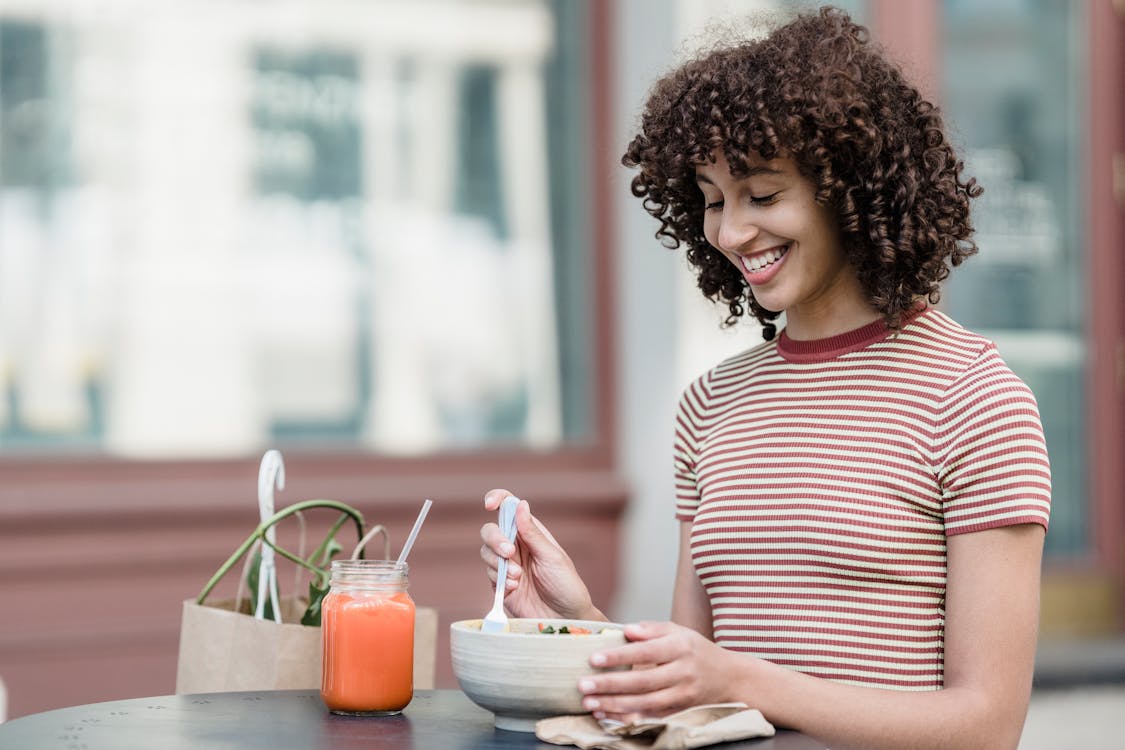 Free Happy ethnic woman at street cafe table with tasty lunch Stock Photo