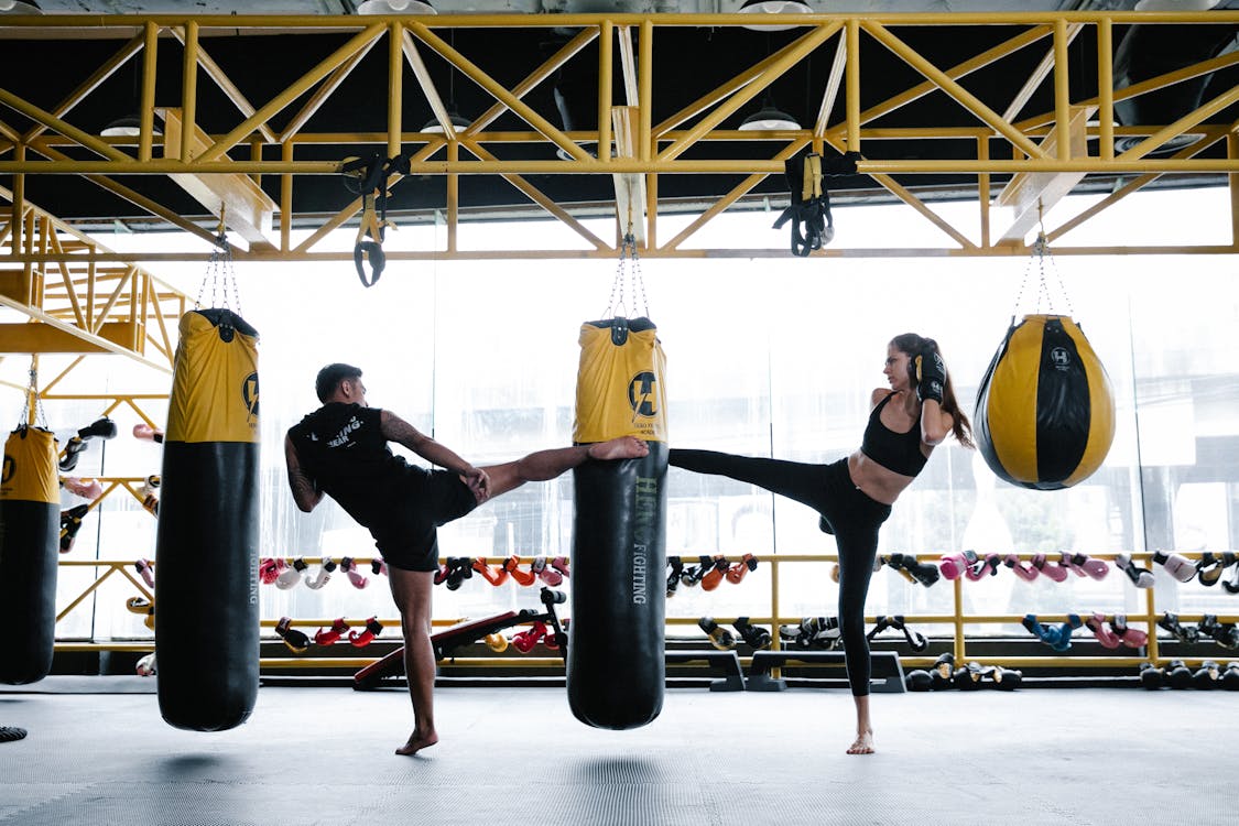 Fit young male and female athletes training on punching bag in gym Stock Photo