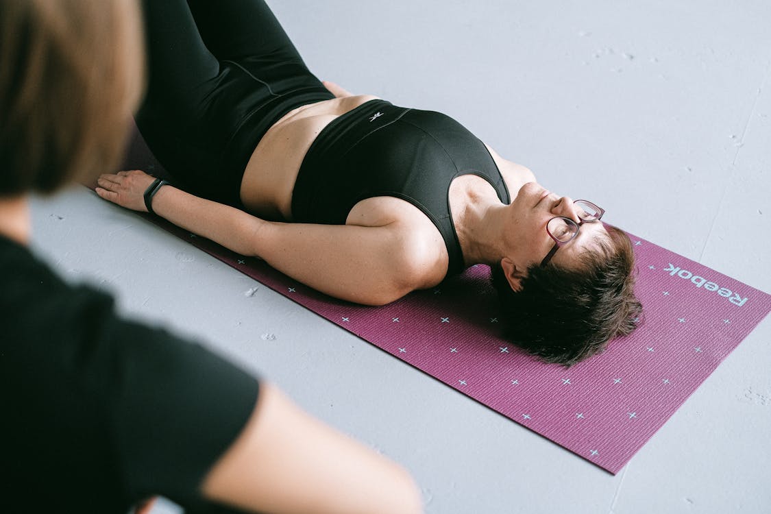 Free A Short Haired Woman Lying on a Yoga Mat Stock Photo