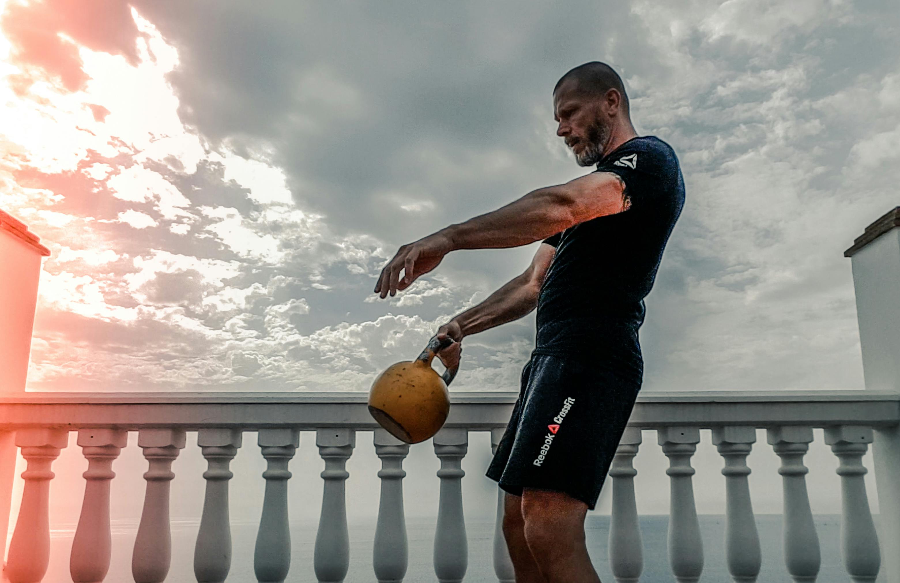 Man in Black Shirt Carrying Kettle Bell Outdoors Stock Photo