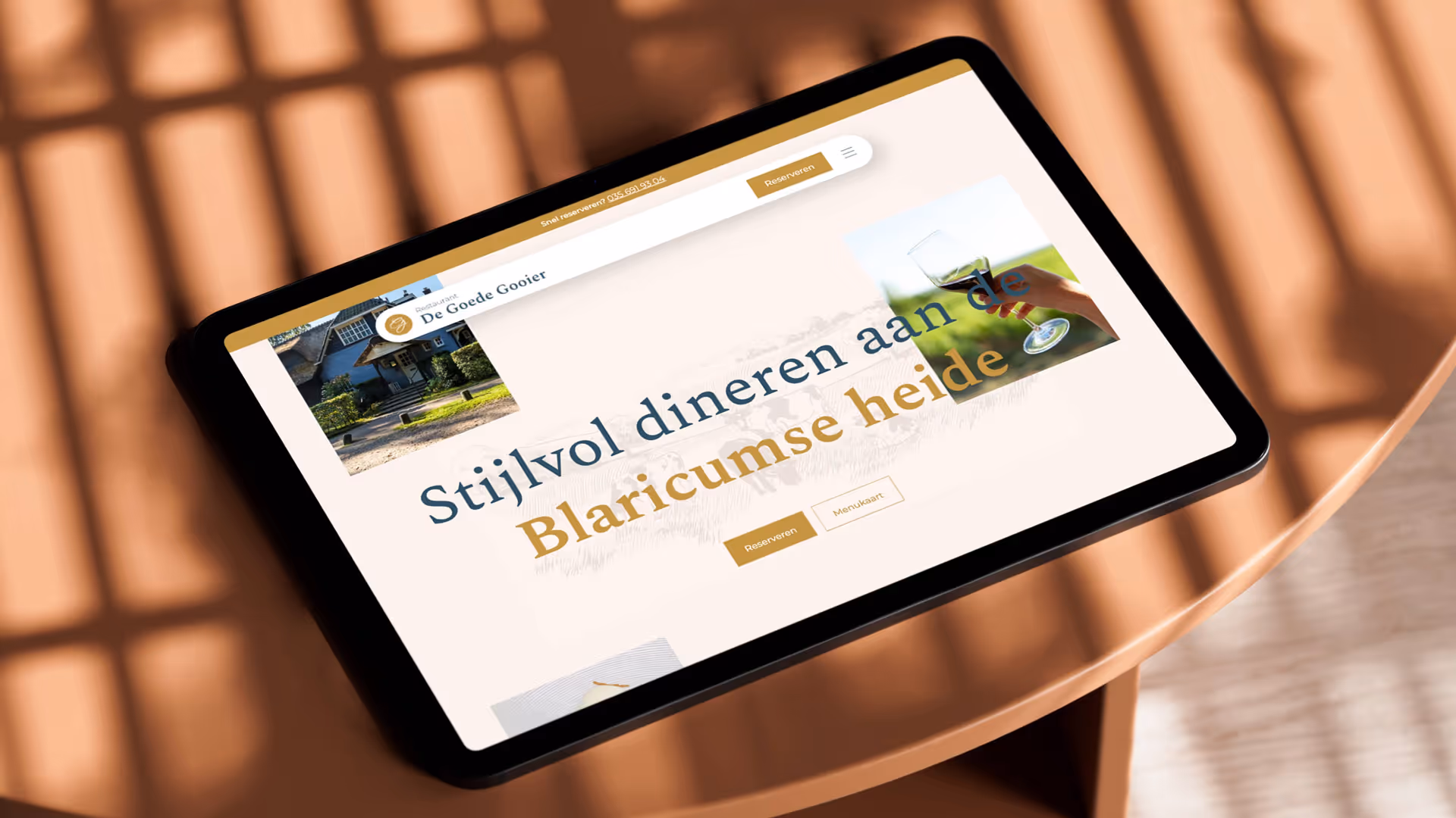 Tablet toont website van restaurant De Goede Gooier met tekst over stijlvol dineren aan de Blaricumse heide en knoppen voor reserveren en menukaart.