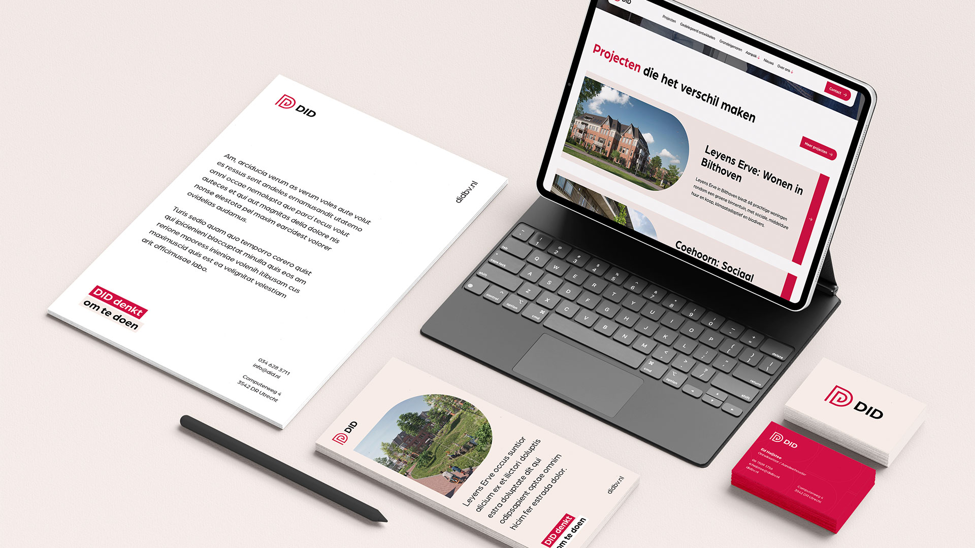 Bureau met tablet met website over woningen, briefpapier, visitekaartjes en pen met DID-logo branding.