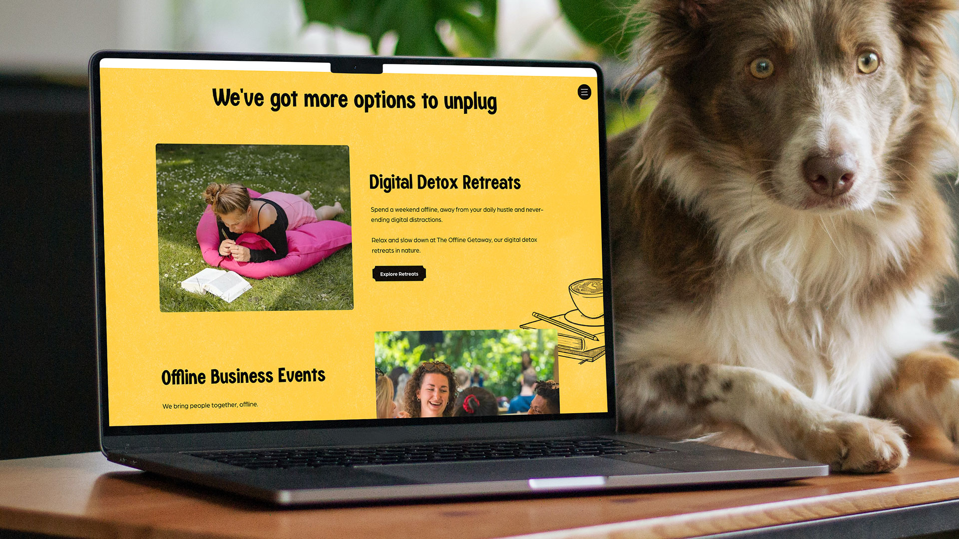 Laptop op een tafel toont een website met gele achtergrond over digitale detox en offline zakelijke evenementen, naast een bruine en witte hond.
